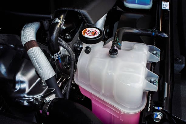 Le compartiment du moteur d'une voiture avec un réservoir de carburant rose.