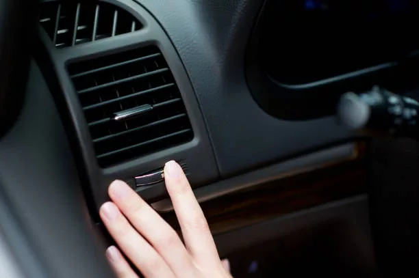 La main d'une femme ajuste la bouche d'aération d'une voiture pour optimiser le système de chauffage et de refroidissement.
