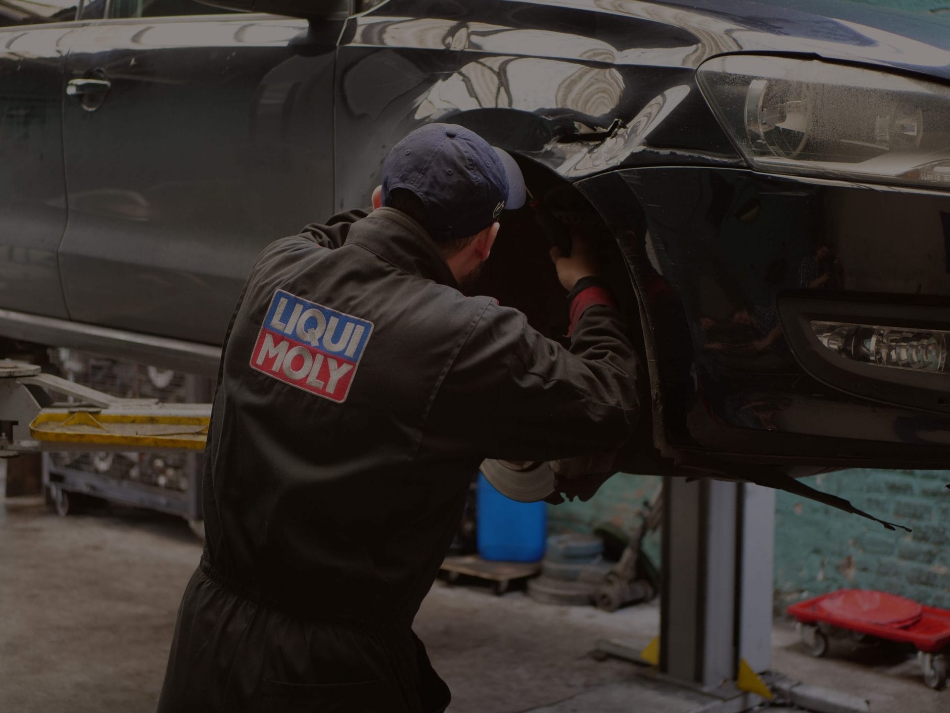 Un homme travaille sur une voiture dans un garage, effectuant l'entretien ou les réparations automobiles.