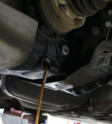 Vidange de l'huile moteur lors d'une révision, affichant le dessous du véhicule.